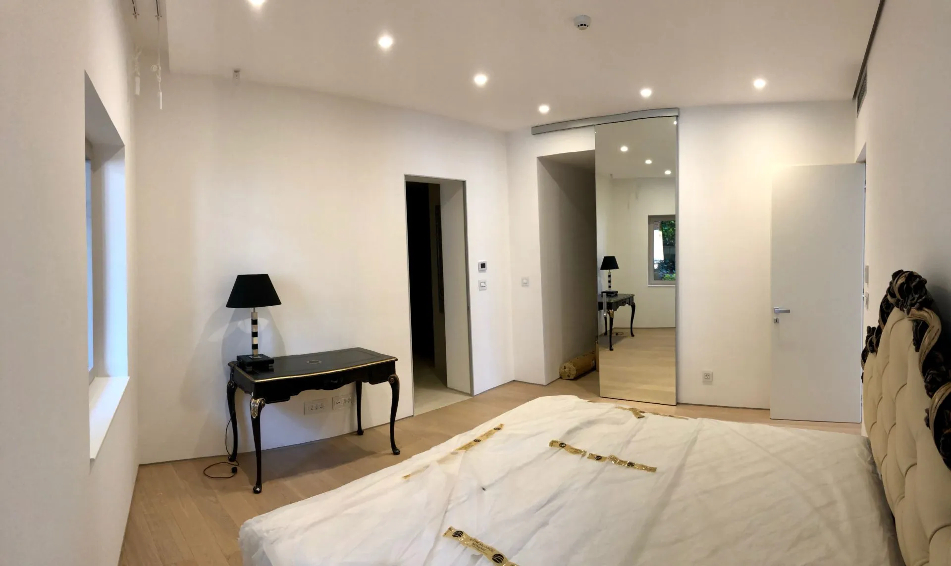 Modernes Schlafzimmer in einer Wohnung in Budva, Montenegro: Doppelbett, Vintage-Tischchen, Spiegel und Spotbeleuchtung.