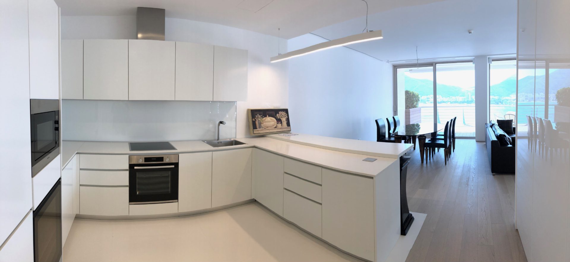 Moderne weiße Küche mit Kochinsel und Panoramablick auf das Meer in einer Wohnung in Budva, Montenegro.