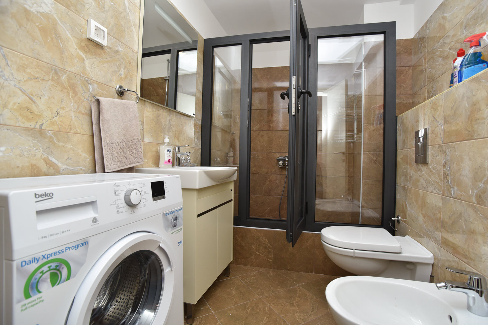 Modernes Badezimmer mit Duschkabine und Waschmaschine in der Wohnung, Budva, Montenegro.