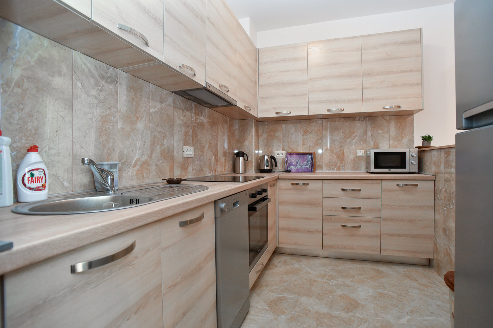 Moderne Küche mit hellen Möbeln und Einbaugeräten in einer zum Verkauf stehenden Wohnung in Budva, Montenegro.