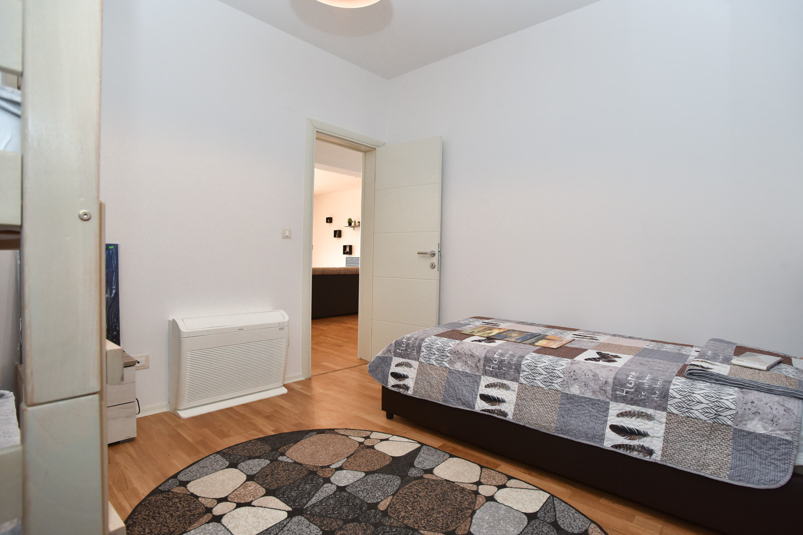 Helles Schlafzimmer mit Einzelbett und Heizung in einer zum Verkauf stehenden Wohnung in Budva, Montenegro.