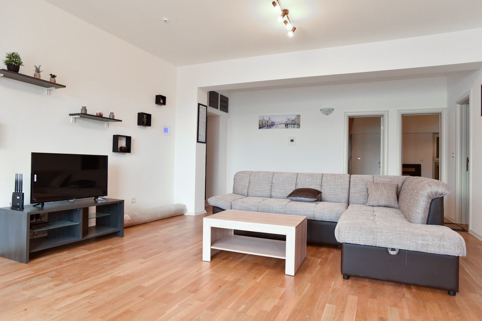 Helles Wohnzimmer in einer Wohnung in Budva, Montenegro: Ecksofa, Couchtisch, TV-Bereich und Parkettboden.