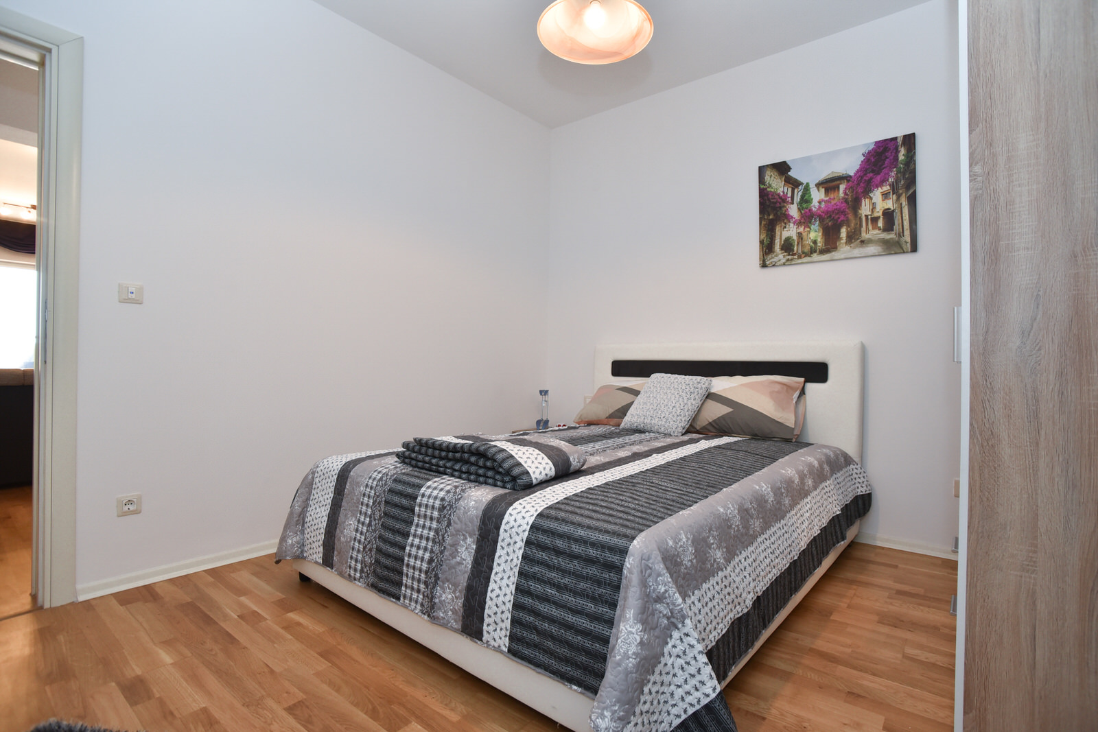Helles Schlafzimmer mit Doppelbett in einer Wohnung in Budva, Montenegro: moderne Ausstattung und Parkettboden.