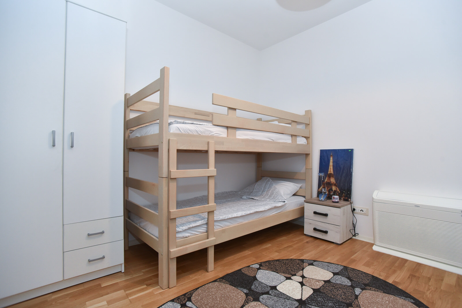 Kinderzimmer mit Etagenbett, weißem Kleiderschrank und Parkett in einer zum Verkauf stehenden Wohnung in Budva, Montenegro.