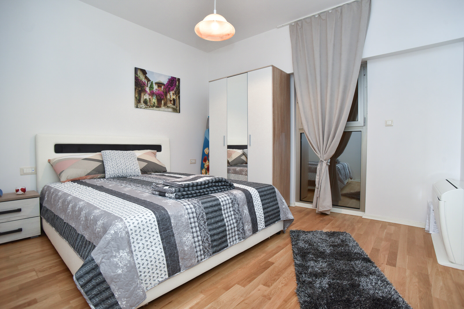 Helles Schlafzimmer mit Doppelbett und Spiegelschrank in einer Wohnung in Budva, Montenegro. Modernes Interieur.