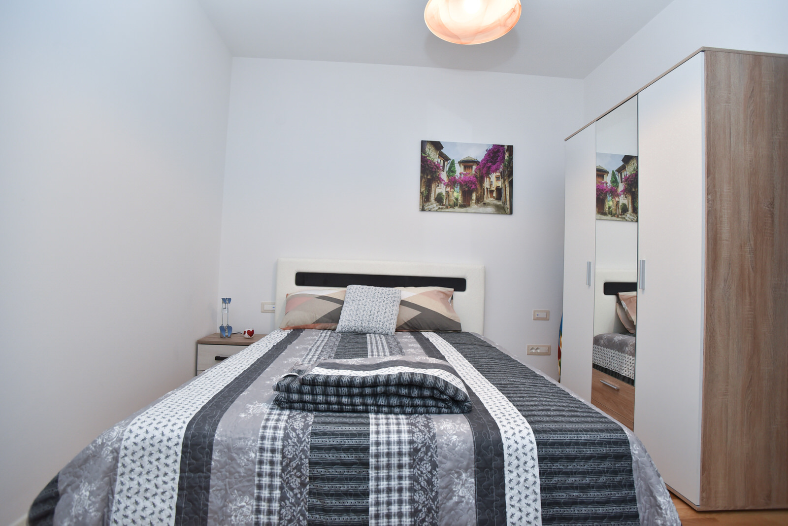 Gemütliches Schlafzimmer mit Doppelbett und Spiegelschrank in einer zum Verkauf stehenden Wohnung in Budva, Montenegro.