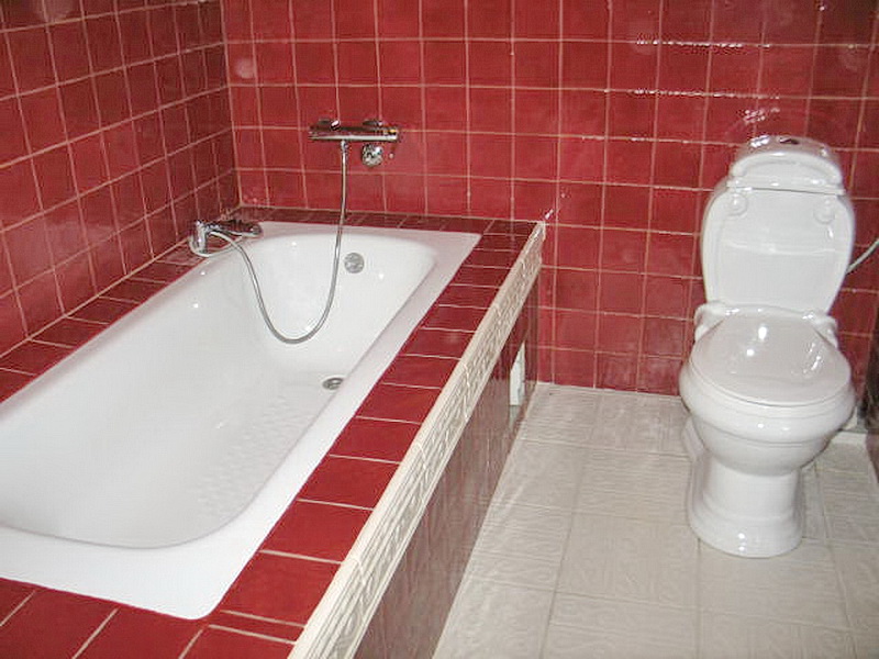Bathroom with red tiles, a white bathtub, and fixtures in a house in Dobri Vody, Montenegro.