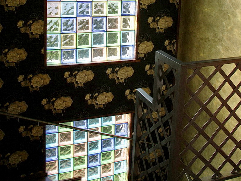 Designer staircase with a lattice railing and a wall of colored glass blocks in a house, Dobri Vody, Montenegro.