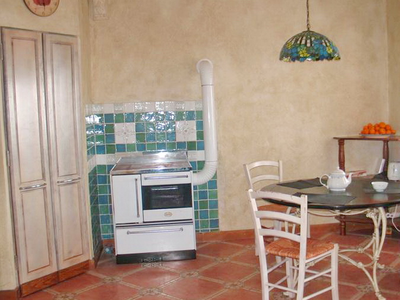 Kitchen in a house in Dobri Vody, Montenegro: vintage stove, tiled backsplash, dining area, and stained-glass lamp.