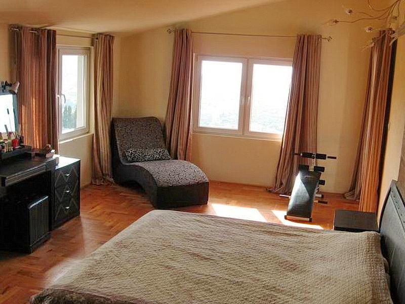 Bedroom in a house in Dobri Vody, Montenegro: double bed, chaise lounge, parquet flooring, and sea view from the windows.