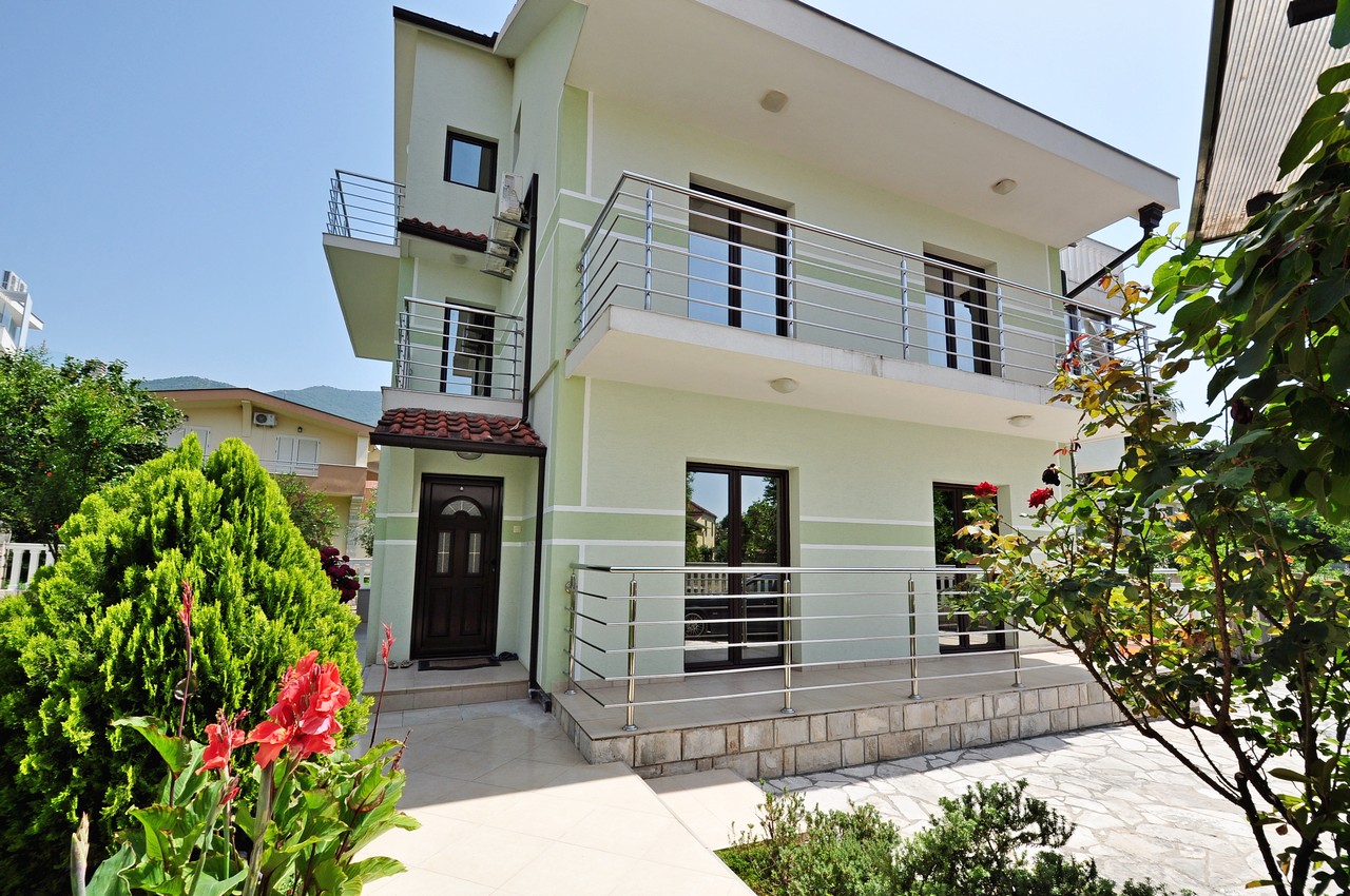 Zweistöckiges Haus mit Terrassen und Garten in Tivat, Montenegro: moderne Fassade, Panoramafenster und gepflegtes Grundstück.