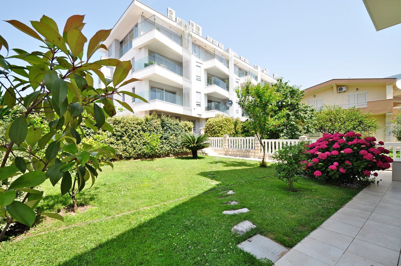 Moderner Wohnkomplex in Tivat, Montenegro, mit gepflegtem grünem Garten, Rasen und blühenden Hortensien.