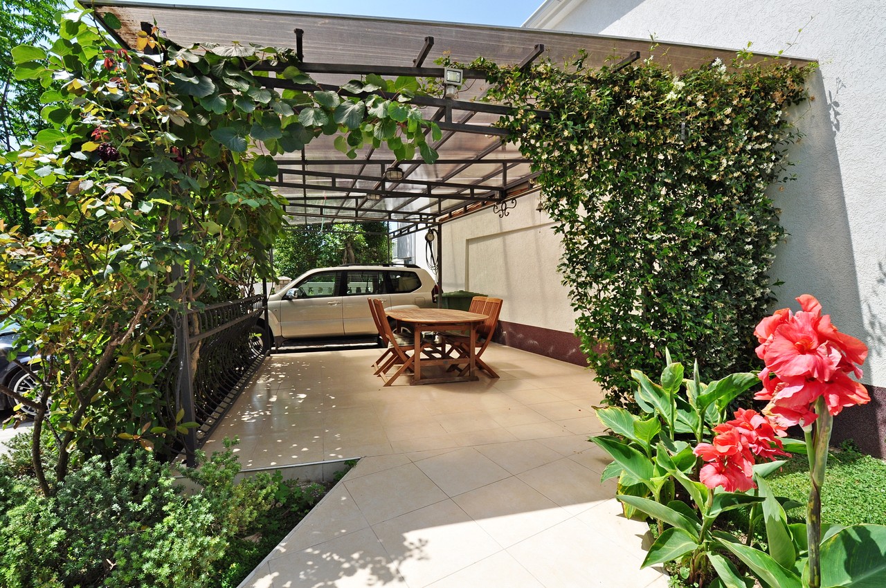 Gemütliche Terrasse mit Überdachung, Holztisch und Garten am Haus in Tivat, Montenegro. Parkplatz im Hof.