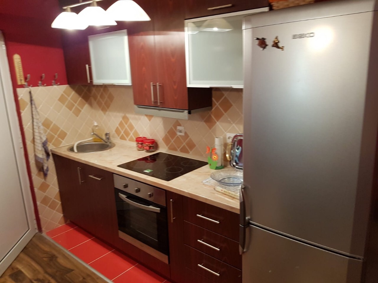 Küche in einer Wohnung in Budva, Montenegro: dunkle Einbauküche, integrierte Geräte, Herd und Kühlschrank von Beko, Fliesen als Spritzschutz.
