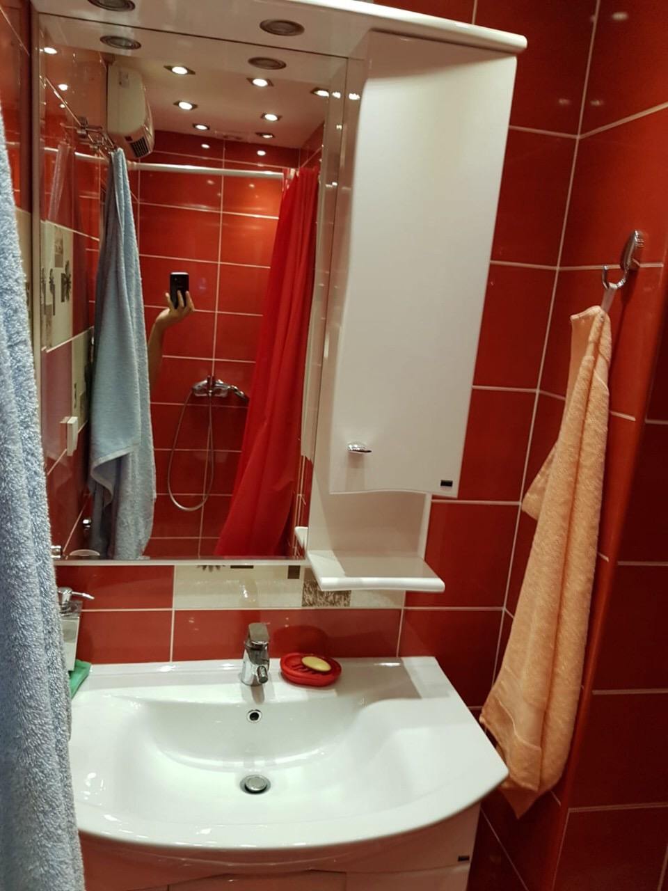 Badezimmer mit roten Fliesen, weißem Waschbecken und Spiegel in einer Wohnung zum Verkauf in Budva, Montenegro.