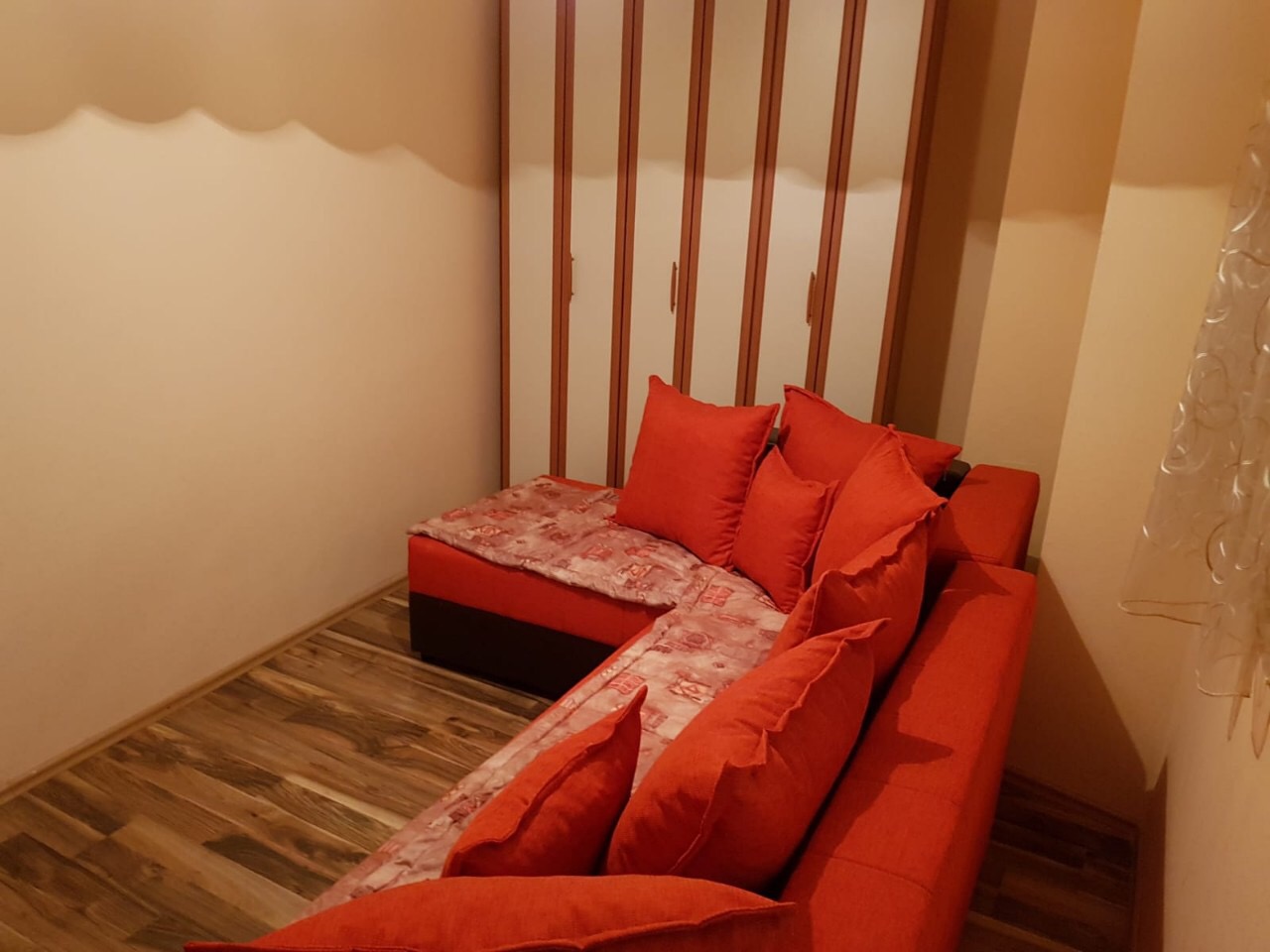 Gemütliches Wohnzimmer mit rotem Ecksofa und Einbauschrank in einer Wohnung, Stadt Budva, Montenegro.