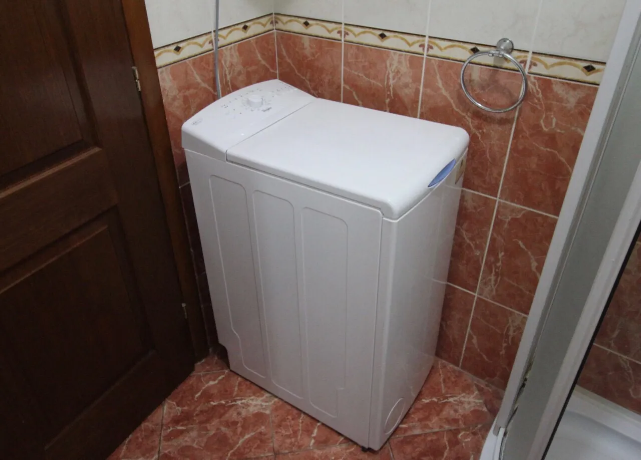 Un lave-linge compact dans une salle de bain carrelée