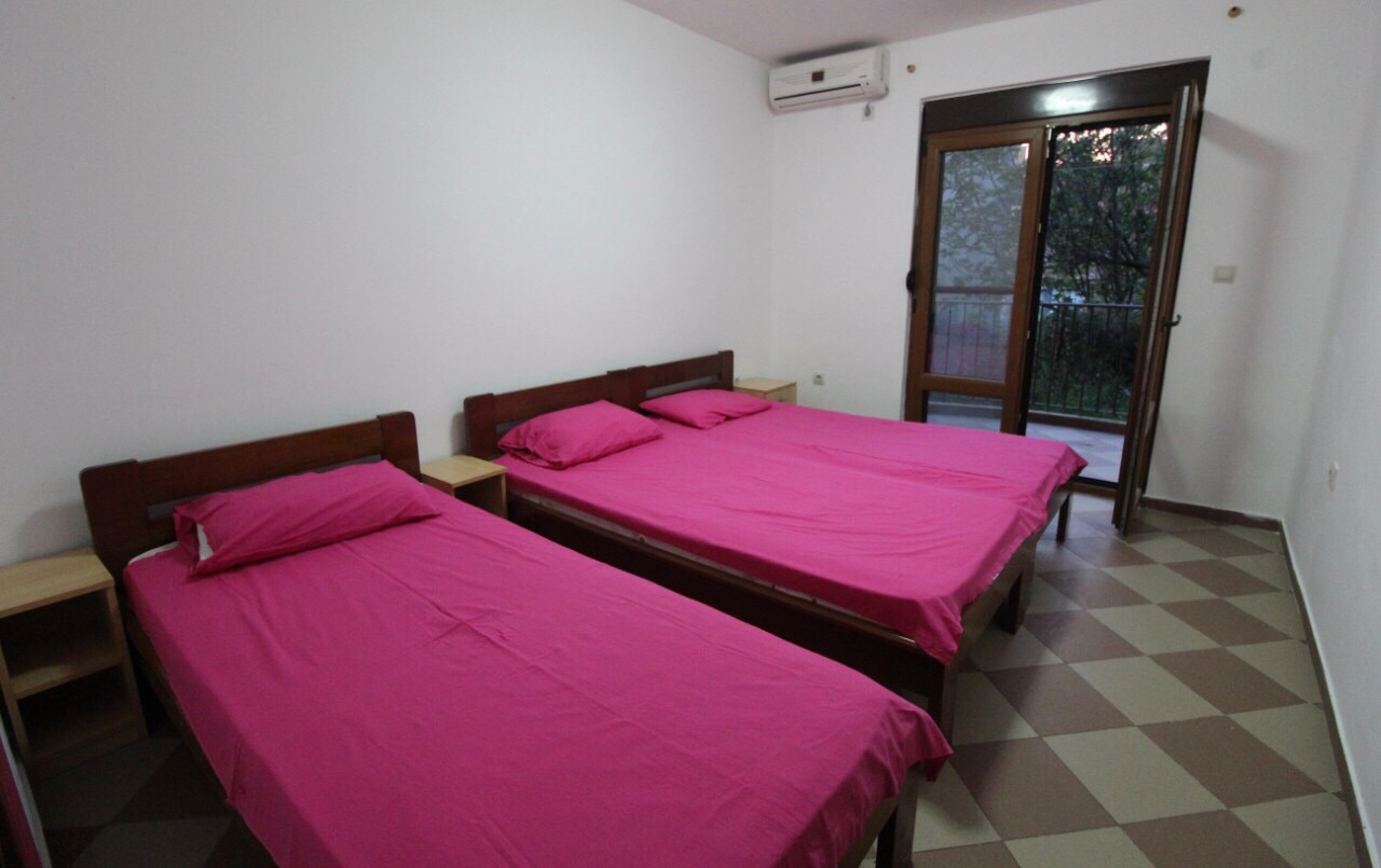 Schlafzimmer mit drei Betten, Fliesenboden und Zugang zum Balkon im Haus, Dobri Vody, Barska Riviera, Montenegro.