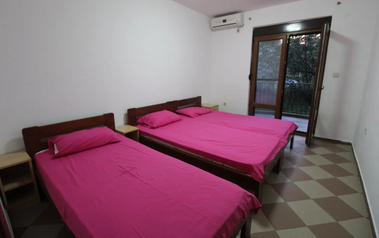 Chambre avec deux lits simples, un lit double et une porte-fenêtre donnant sur le balcon.
