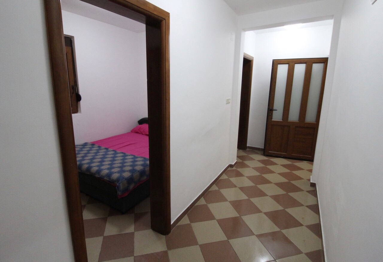 Flur und Eingang zum Schlafzimmer mit Bett im Haus an der Bar Riviera, Montenegro: Fliesenboden und Holztüren.