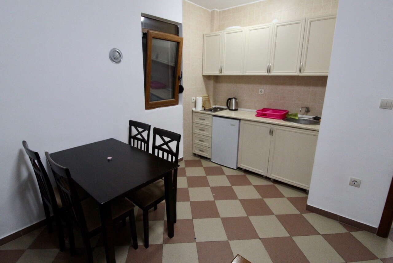 Küche mit Essbereich im Haus, Dobri Vody, Barska Riviera, Montenegro: helle Küchenzeile und dunkler Tisch mit Stühlen.