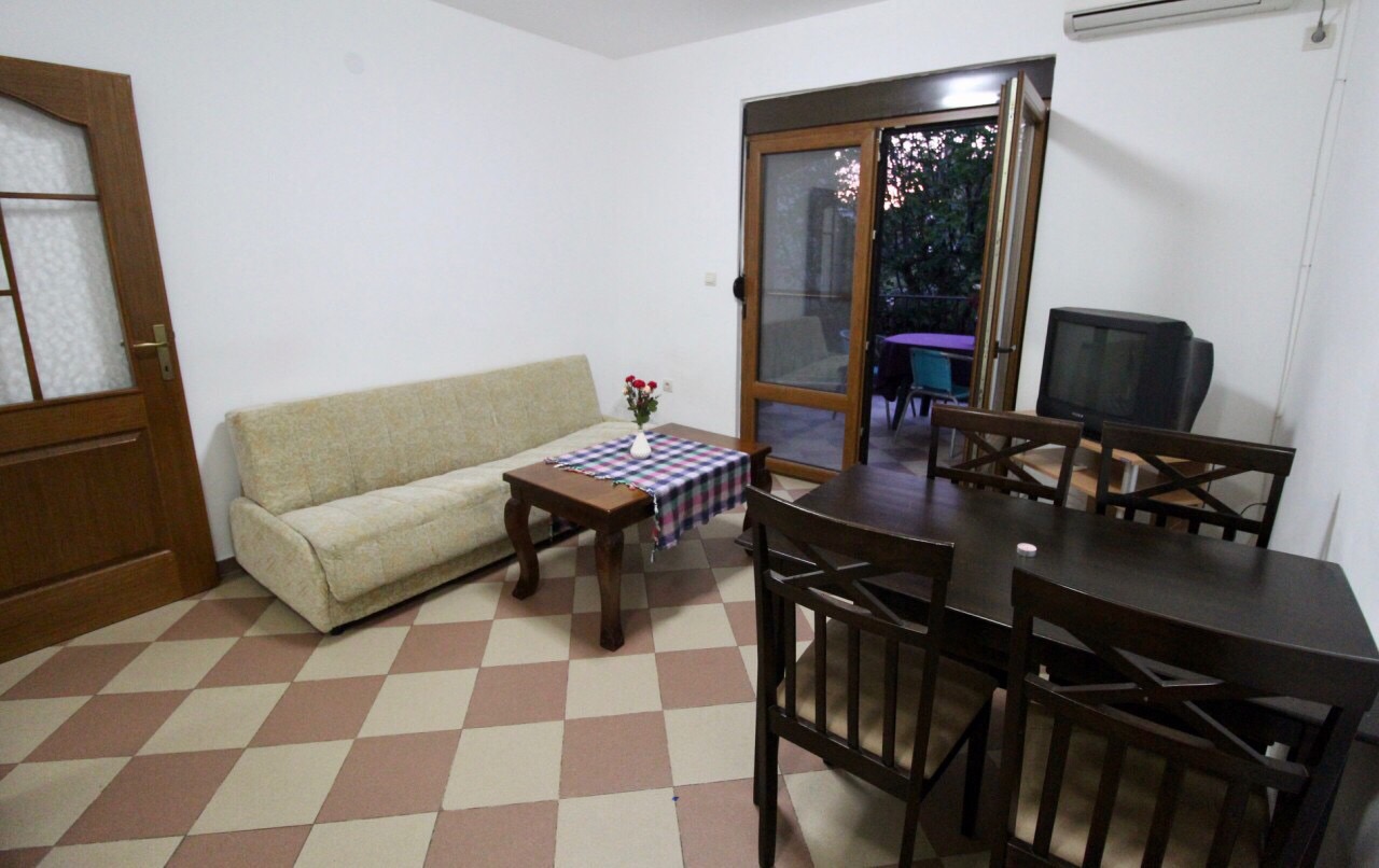 Wohnzimmer in einem Haus in Dobri Vody, Montenegro: heller Raum mit Sofa, Esstisch und Zugang zur Terrasse.