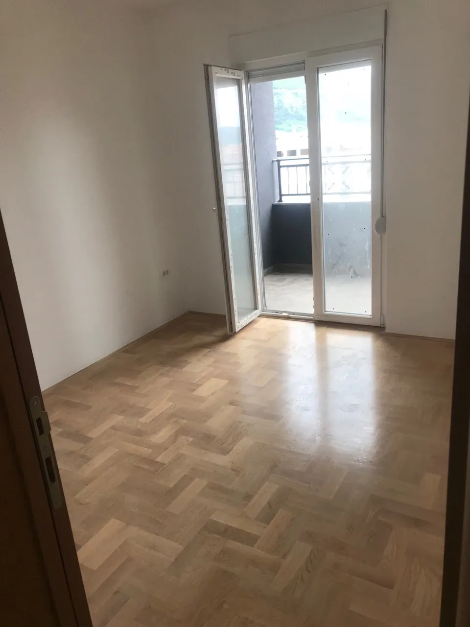 Helles Schlafzimmer mit Parkett und Zugang zum Balkon in einer Wohnung, Budva, Montenegro.