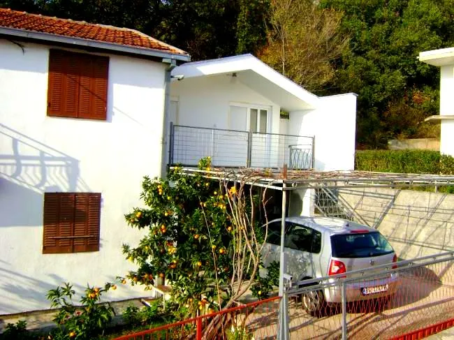 Bela kuća sa krovom od crepa, terasom i citrusnim drvetom u bašti, Šušanj, Crna Gora.