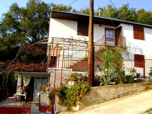 Dvospratna kuća u Šušnju, Crna Gora: fasada sa terasom, vinovom lozom i spoljnim stepeništem na drugi sprat.
