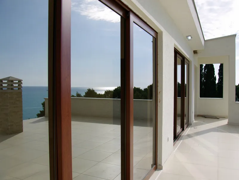 Modernes Landhaus mit großer Glasfassade, die das Meer widerspiegelt.