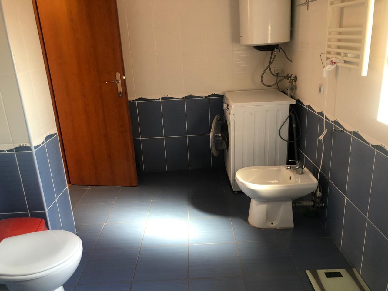 Badezimmer in einer Wohnung in Bečići, Montenegro: blaue Fliesen, Bidet, Waschmaschine und Warmwasserboiler.