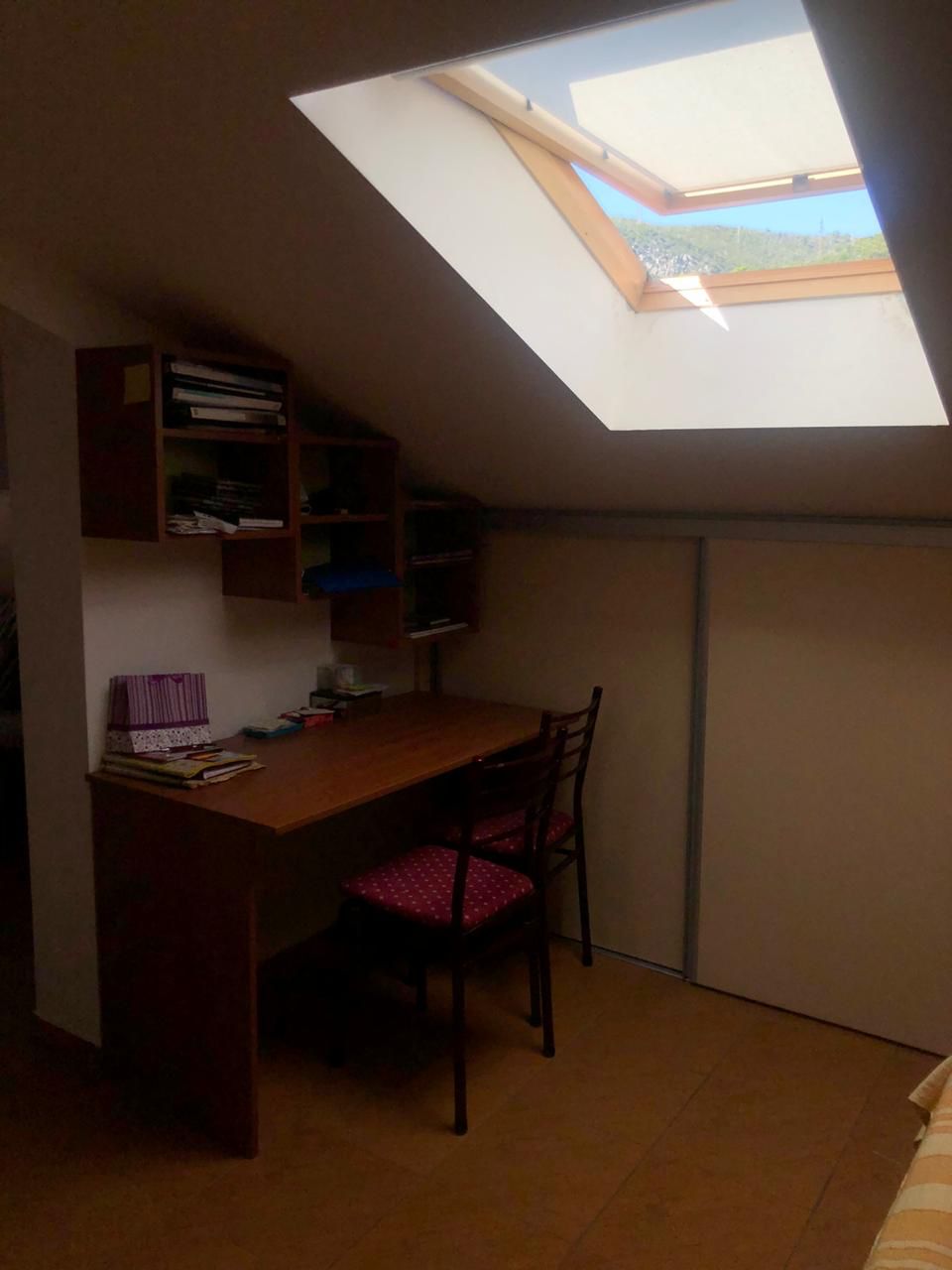 Arbeitsbereich im Dachgeschoss-Schlafzimmer der Wohnung in Bečići, Montenegro, mit Schreibtisch und Dachfenster.