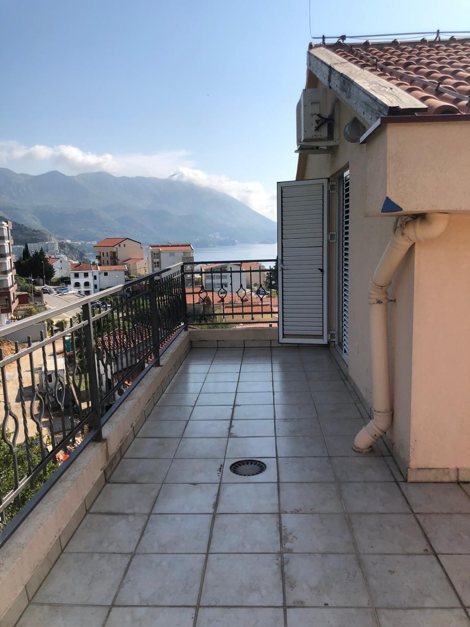 Geräumiger Balkon der Wohnung in Bečići, Montenegro, mit Panoramablick auf das Meer, die Berge und die Stadtbebauung.