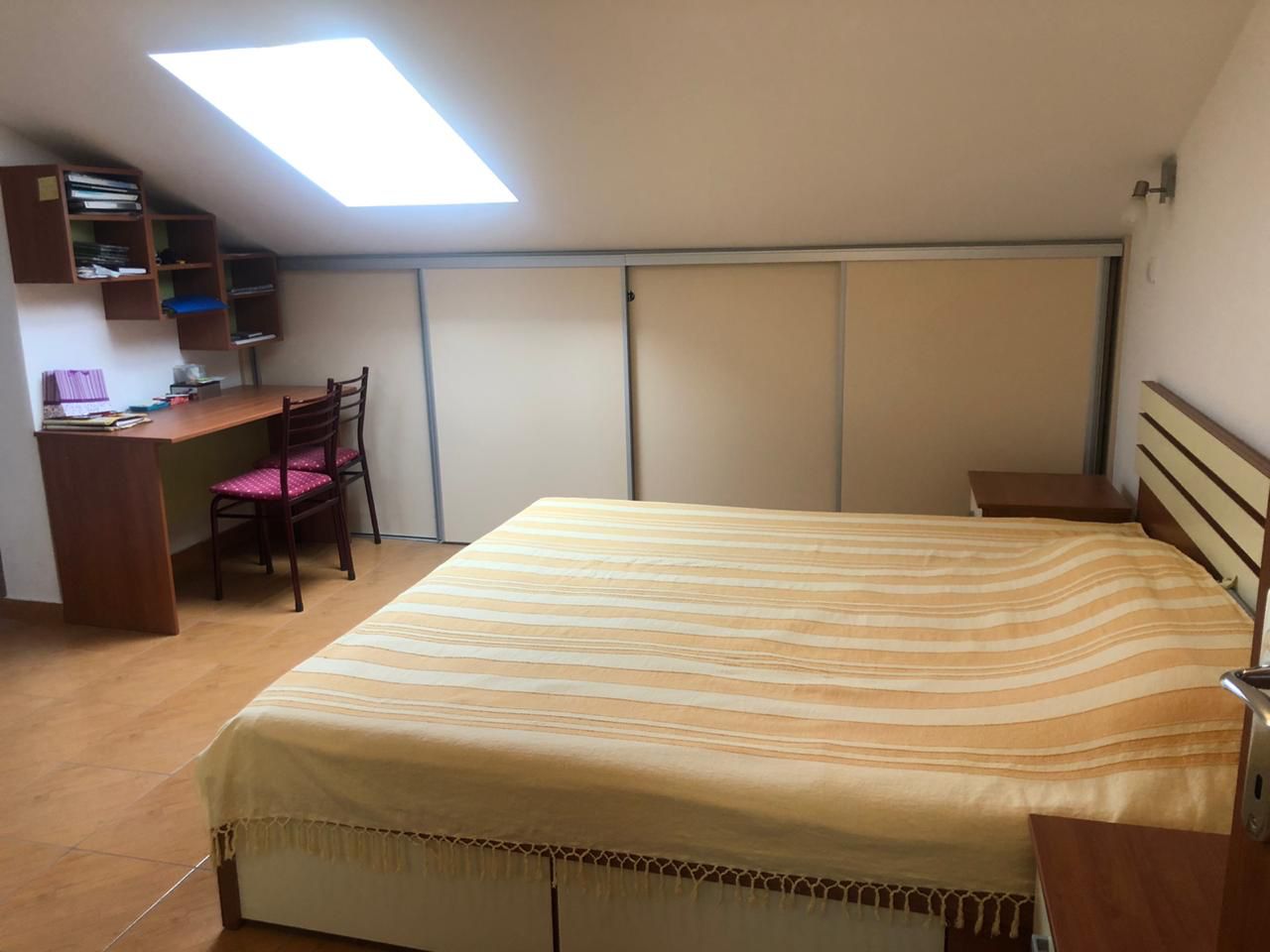 Schlafzimmer in einer Dachgeschosswohnung in Bečići, Montenegro: Doppelbett, Einbauschrank und Schreibtisch am Fenster.