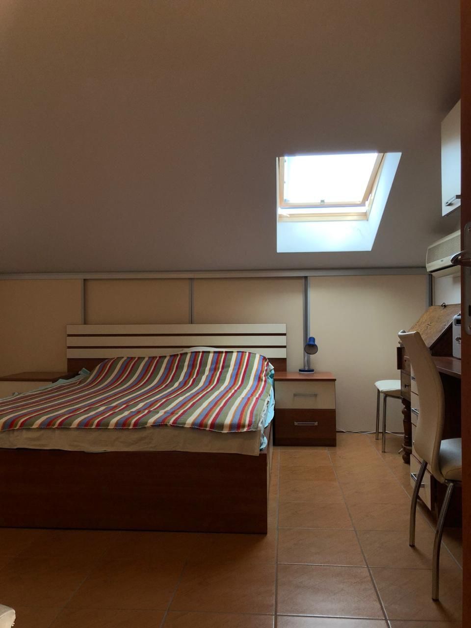 Schlafzimmer in einer Dachgeschosswohnung in Bečići, Montenegro: Doppelbett, Schreibtisch und Dachfenster.
