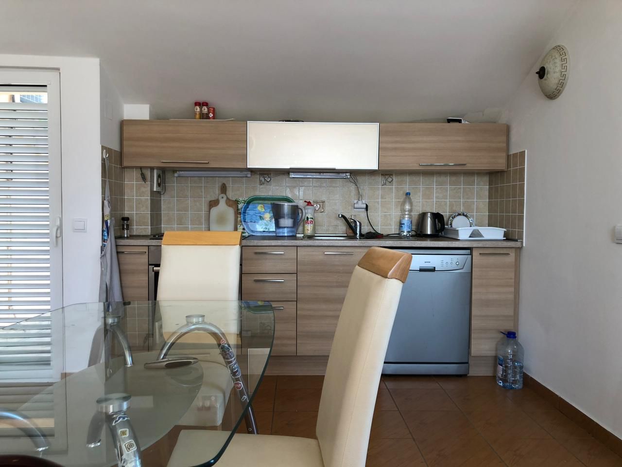 Küche mit Holz-Einbauküche und Essbereich in einer Wohnung in Bečići, Montenegro. Gemütliches Interieur mit moderner Ausstattung.