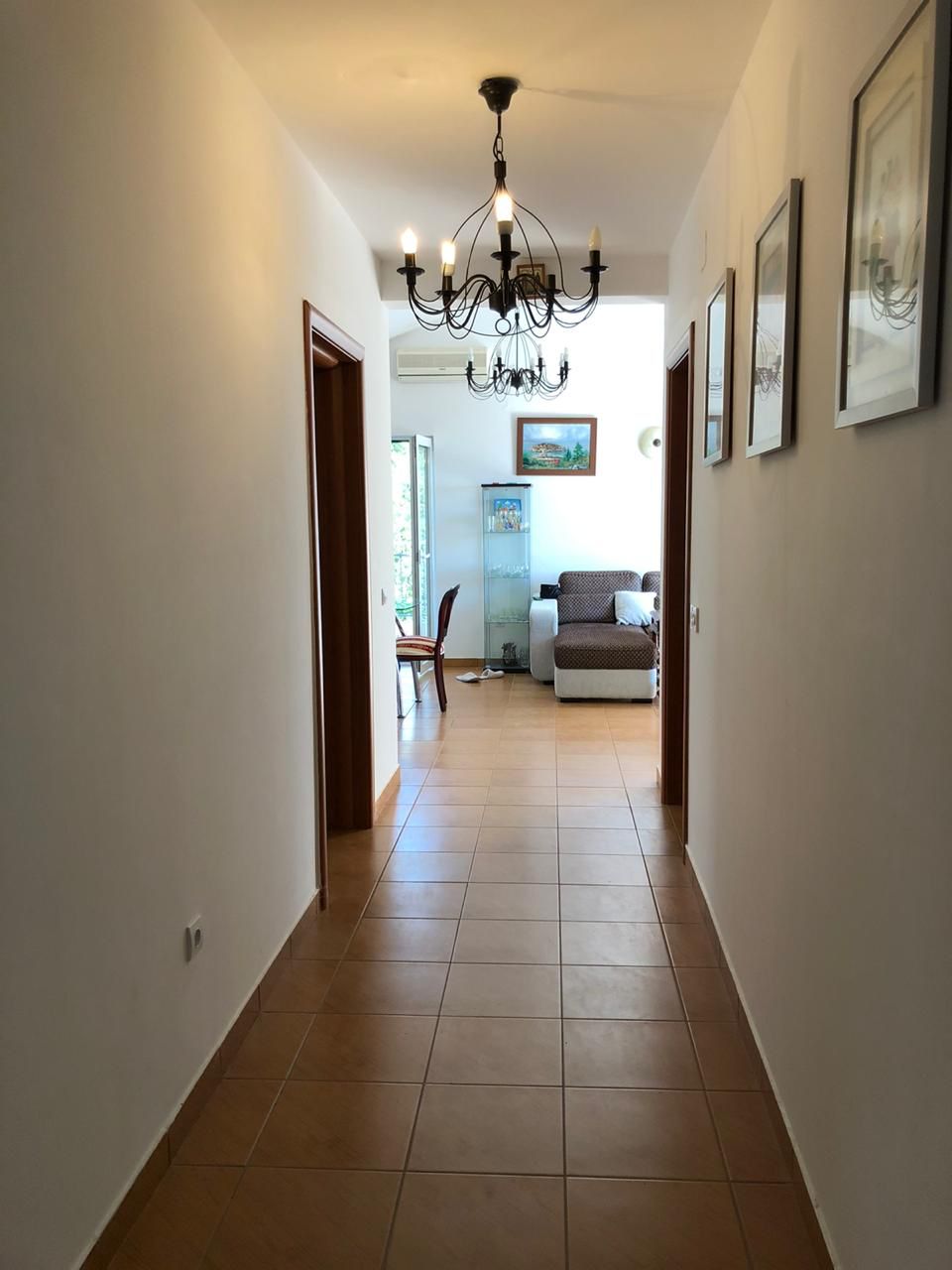 Heller Flur mit Fliesen und schmiedeeinem Kronleuchter, der ins Wohnzimmer der Wohnung in Bečići, Montenegro führt.