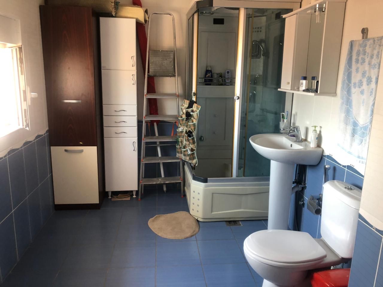 Badezimmer in einer Wohnung in Bečići, Montenegro: Duschkabine, Aufbewahrungsschränke, Waschbecken und Sanitäranlagen.