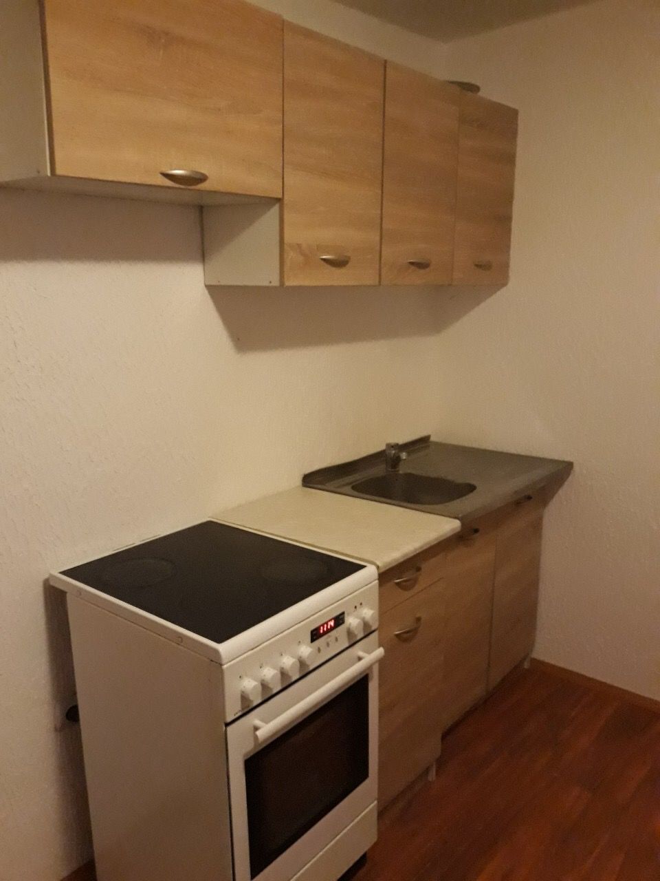 Kompaktowa kuchnia w domu w Žanjicach, Czarnogóra: jasna zabudowa, płyta elektryczna i zlewozmywak, laminat na podłodze.