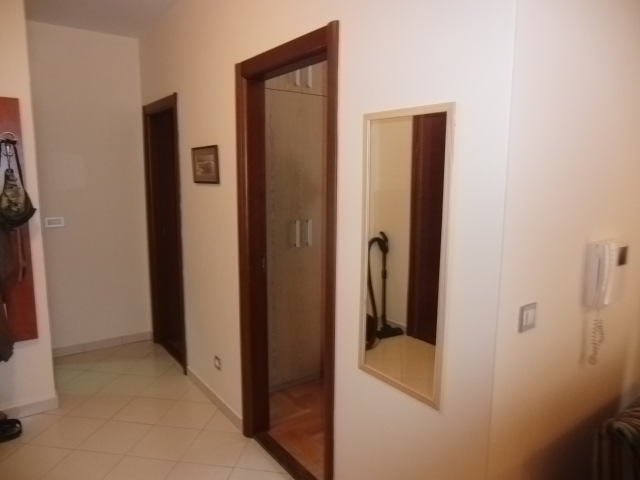 Heller Flur in einer Wohnung in Budva, Montenegro: Innentüren, Einbauschrank, Spiegel und Fliesenboden.