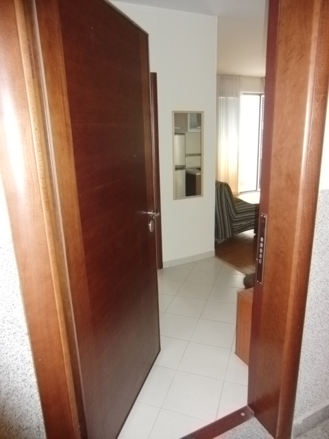 Blick vom Flur ins Wohnzimmer einer Wohnung in Budva, Montenegro: helle Fliesen, Holztüren und weiche Möbel.