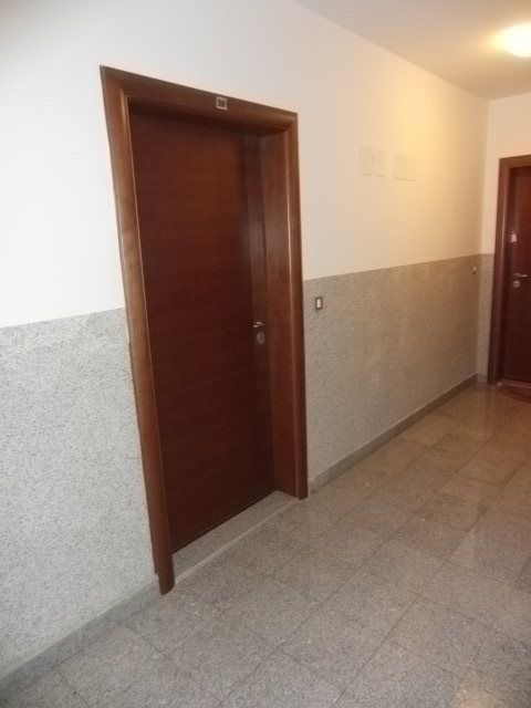 Flur mit Holztür und Steinverkleidung an den Wänden in einer Wohnanlage, Stadt Budva, Montenegro.