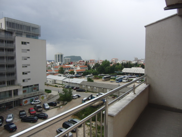 Blick vom Balkon einer Wohnung in Budva, Montenegro: Stadtpanorama, Parkplatz und Wohnhäuser in fußläufiger Entfernung.