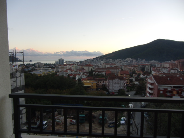 Blick vom Balkon der Wohnung in Budva, Montenegro: Panoramablick auf die Stadt, Berglandschaft und Meereshorizont bei Sonnenuntergang.