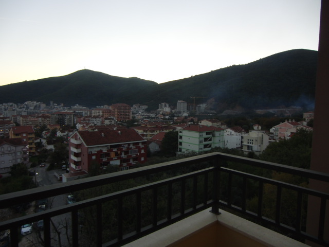 Blick vom Balkon einer Wohnung in Budva, Montenegro: Panorama der Stadt, Wohnhäuser und Berglandschaft bei Sonnenuntergang.