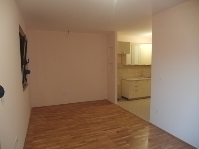 Helles Wohnzimmer mit Parkett und Küchenbereich in einer zum Verkauf stehenden Wohnung in Budva, Montenegro.