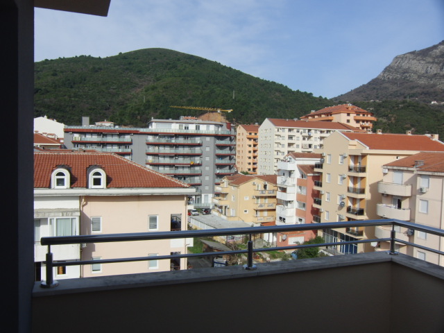Blick vom Balkon der Wohnung in Budva, Montenegro: Panoramablick auf die Stadt, Wohnhäuser mit Ziegeldächern und grüne Berge.