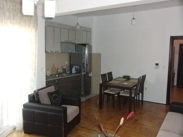 Wohnzimmer mit Essbereich und Küche in einer Wohnung in Budva, Montenegro: Parkett, moderne Möbel und helles Interieur.