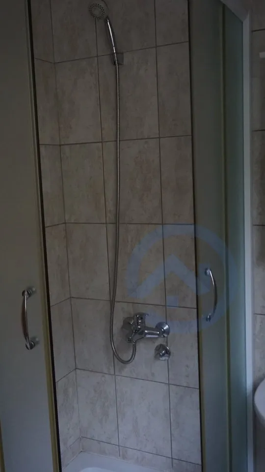 Shower cabin with beige tiles in the bathroom of a house in Kavac, Montenegro. Modern plumbing and finishes.