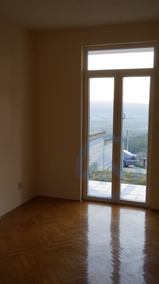 Svetla dnevna soba sa parketnim podom i izlazom na terasu u kući, Kavač, Crna Gora. Pogled na planine i okolinu.
